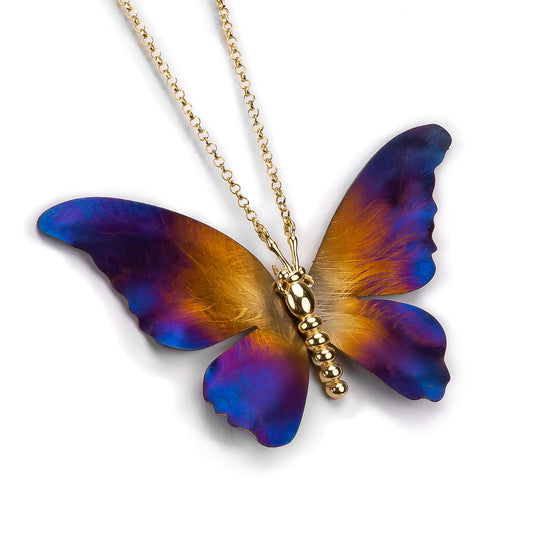 Butterfly-shaped pendant on a gold chain against a white background